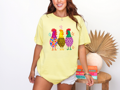 Woman wearing a cornsilk-yellow graphic tee featuring three colorful chickens with stars