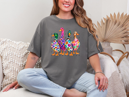 Woman wearing a charcoal-gray graphic tee featuring four colorful floral and leopard-print ducks