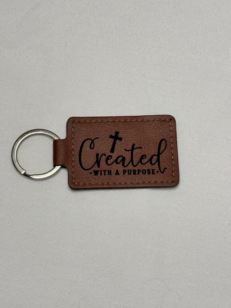 Brown leather keychain with 'Created with a Purpose' text on a gray background