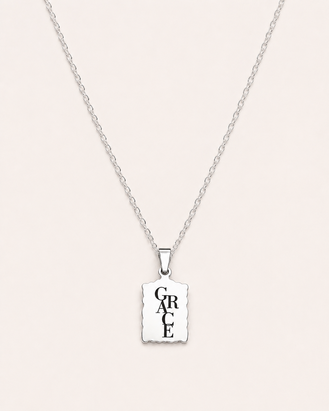 Silver necklace with a square pendant displaying the word 'GRACE' on a light gray background