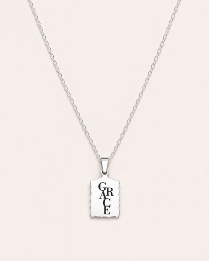 Silver necklace with a square pendant displaying the word 'GRACE' on a light gray background