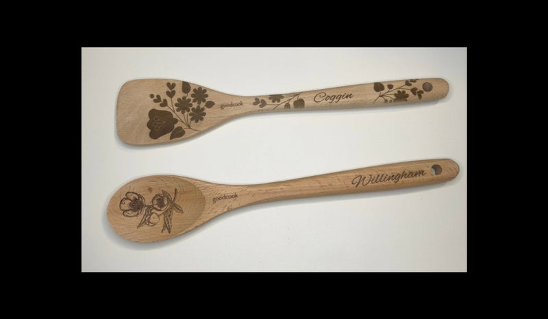 Two wooden spoons with engraved designs and branding on a white background