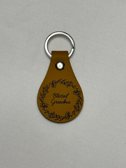 Mustard teardrop keychain engraved with “Blessed Grandma” script surrounded by a floral wreath.