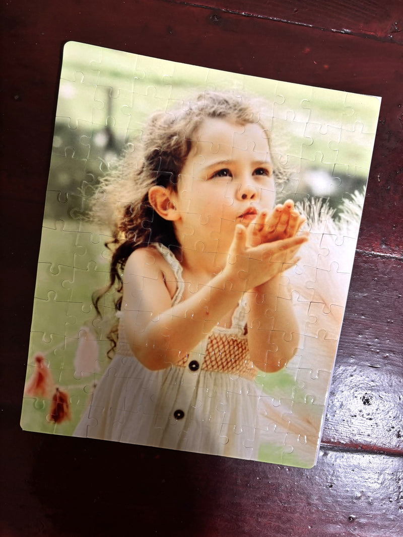 Jigsaw puzzle with a picture of a young girl blowing bubbles on a wooden surface