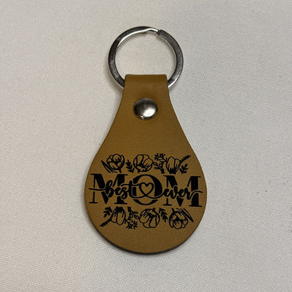 Tan teardrop keychain laser engraved with “Best Mom Ever” lettering, a heart and floral accents.
