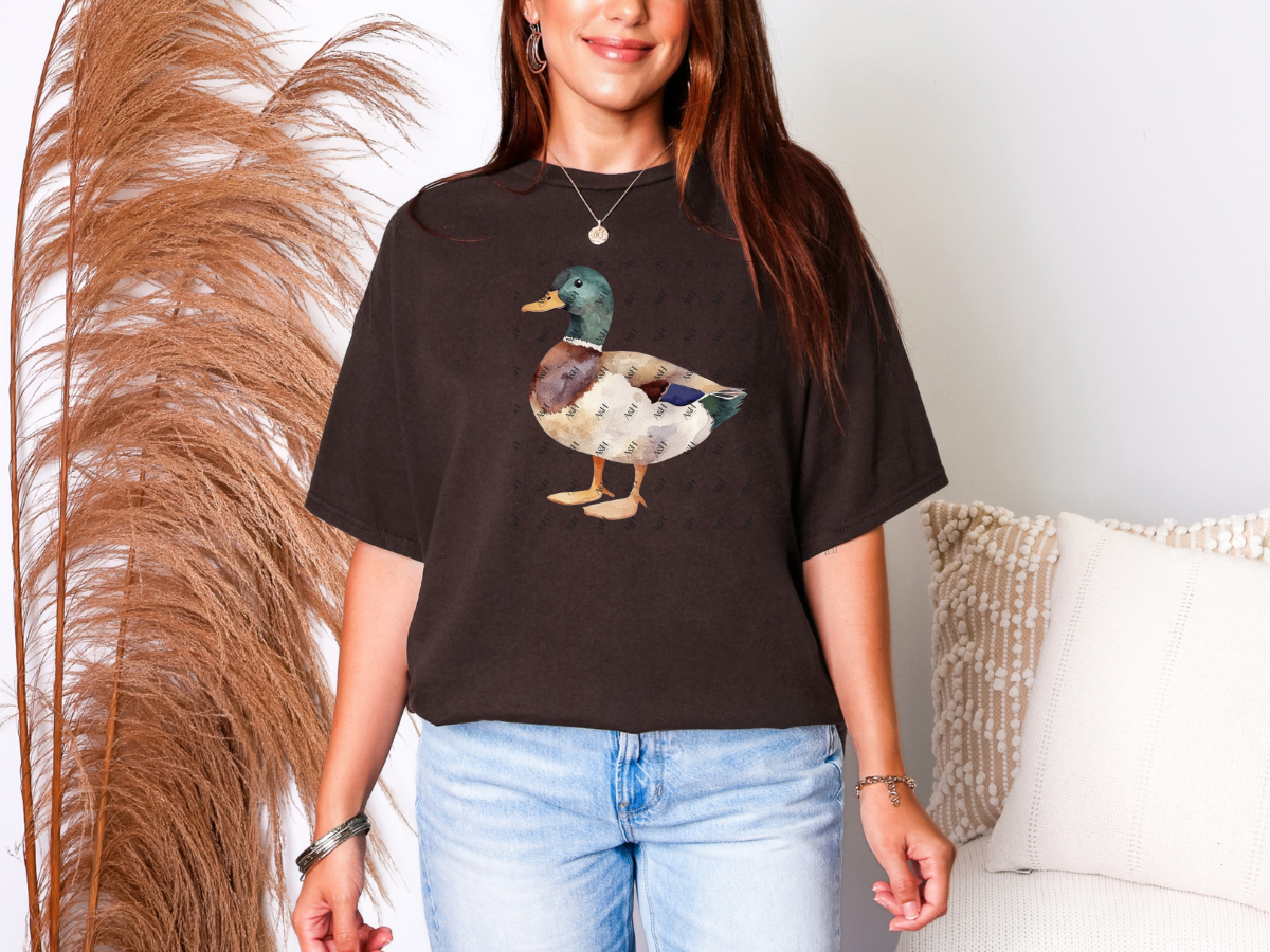 Woman wearing a dark neutral graphic tee featuring an earthy watercolor mallard duck illustration