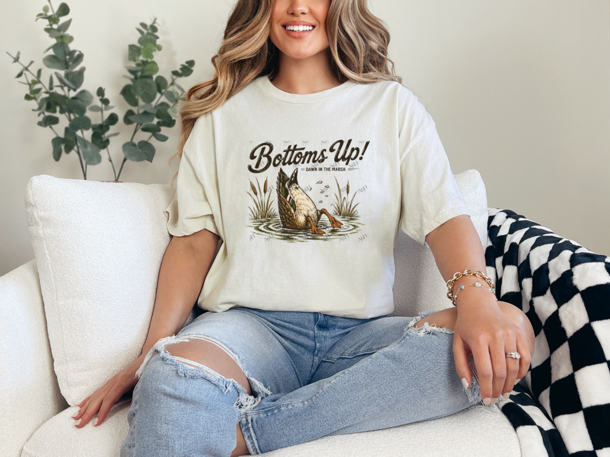 Woman wearing an natural Bottoms Up duck graphic tee featuring a vintage diving duck in a marsh
