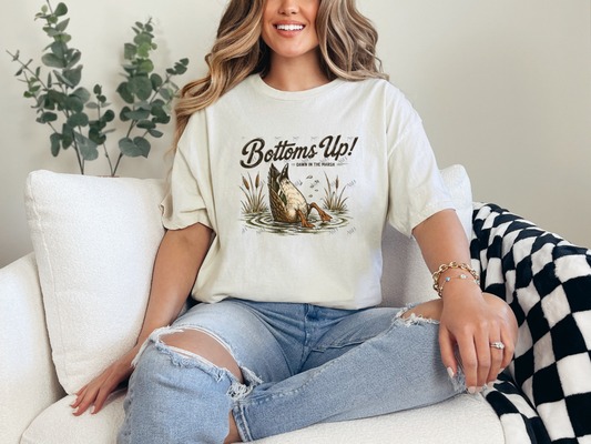 Woman wearing an natural Bottoms Up duck graphic tee featuring a vintage diving duck in a marsh