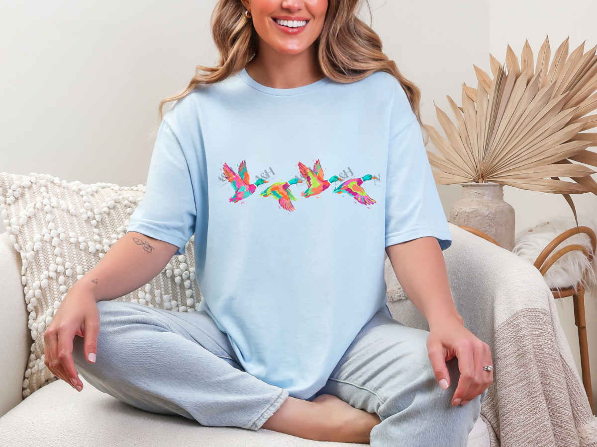 Woman wearing a light blue colorful flying ducks graphic tee
