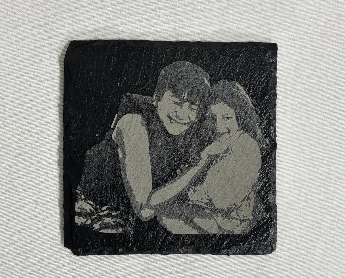 Square black slate coaster laser engraved with a custom photo of two children.