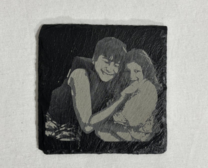 Square black slate coaster laser engraved with a custom photo of two children.