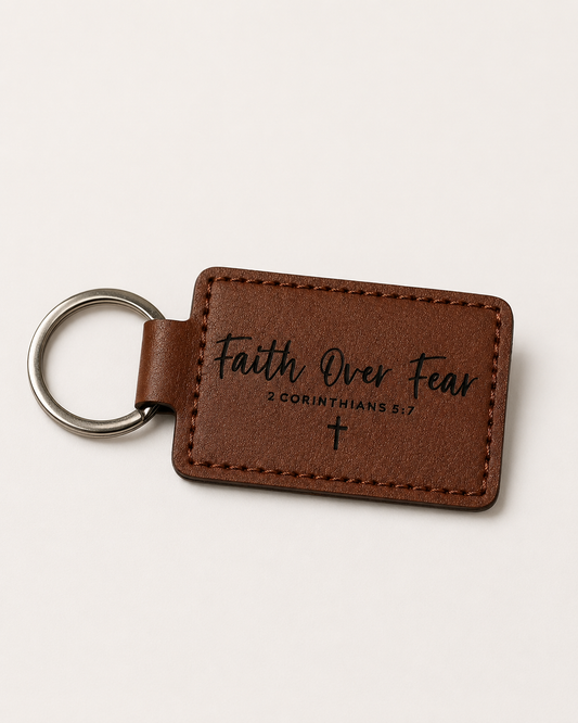 Brown leatherette keychain laser engraved with the words Faith Over Fear, 2 Corinthians 5:7, and a cross.