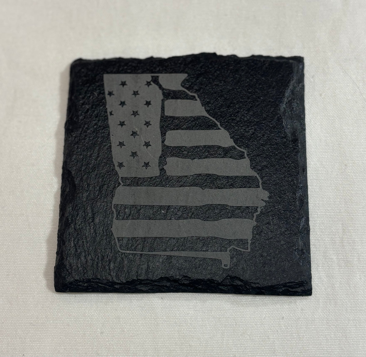 Square black slate coaster engraved with a Georgia state silhouette filled with American flag stars and stripes.