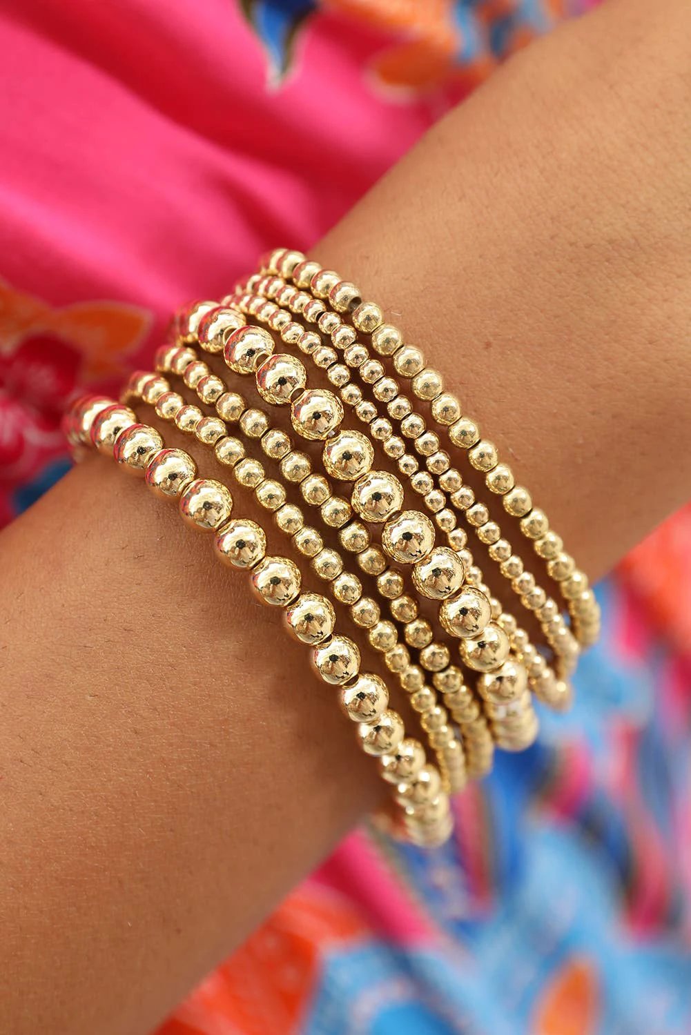 Gold beaded bracelet stack styled on wrist with mixed-size layering bracelets