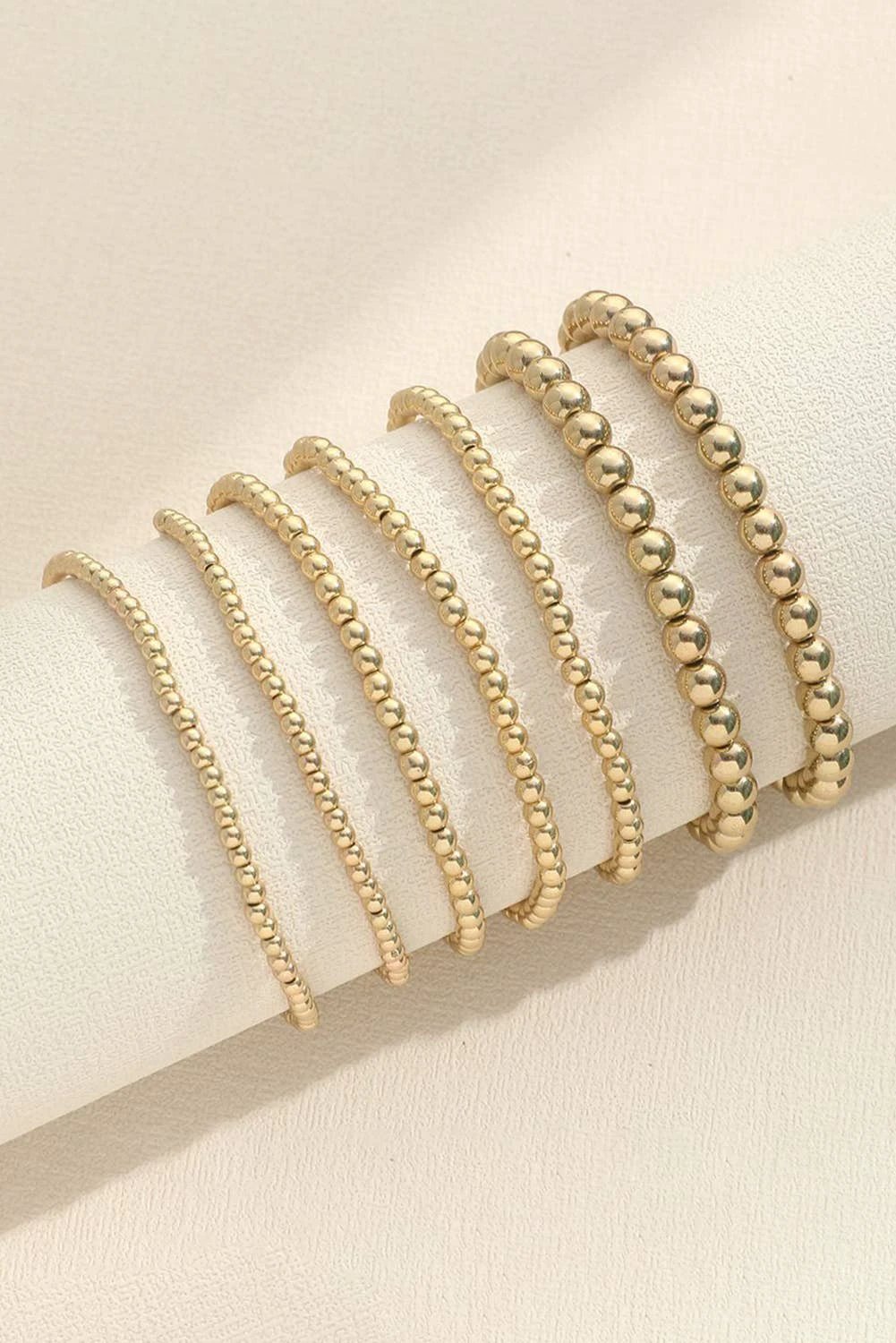 Stackable gold beaded bracelet set featuring mixed round bead sizes