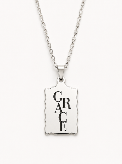 Minimalist silver Christian necklace featuring a scalloped bar pendant engraved with the word "Grace" in elegant black typography.
