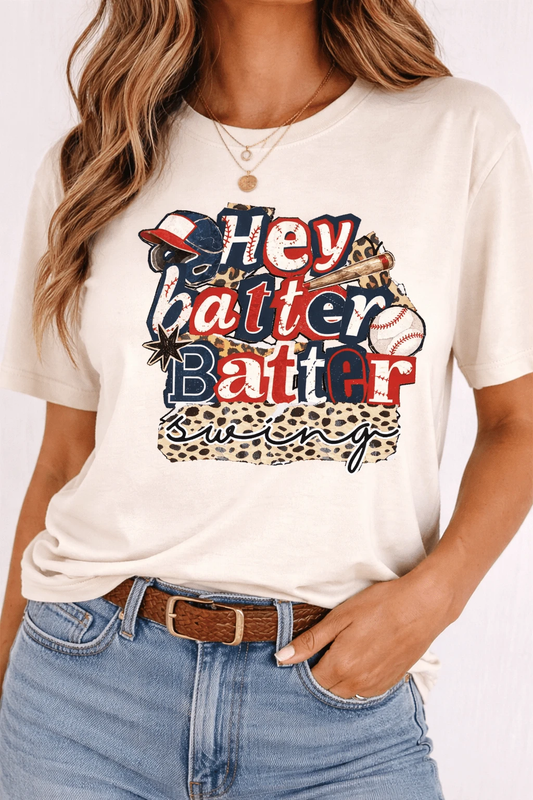 Woman wearing a cream Hey Batter Batter Swing baseball graphic tee with red, navy and leopard-print details