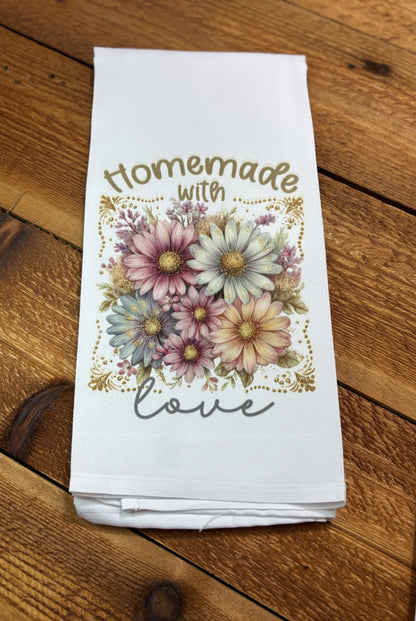 White kitchen tea towel with pastel pink, blue, and cream daisies and gold accents reading “Homemade with Love,” part of a floral tea towel set