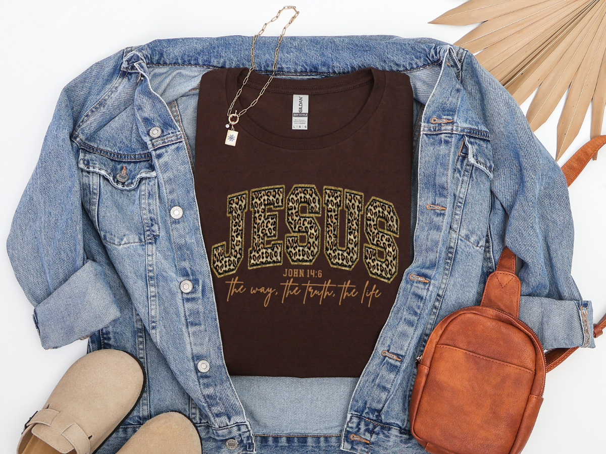 Dark chocolate Jesus John 14:6 Christian graphic tee with leopard-print varsity lettering in a styled flat-lay.