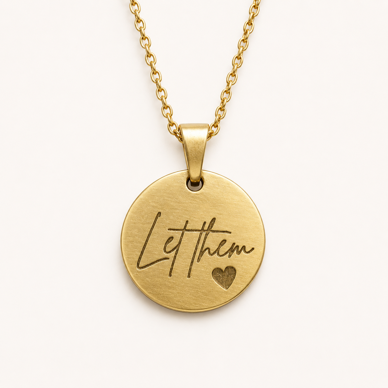Gold-tone round pendant necklace engraved with Let Them script and a small heart