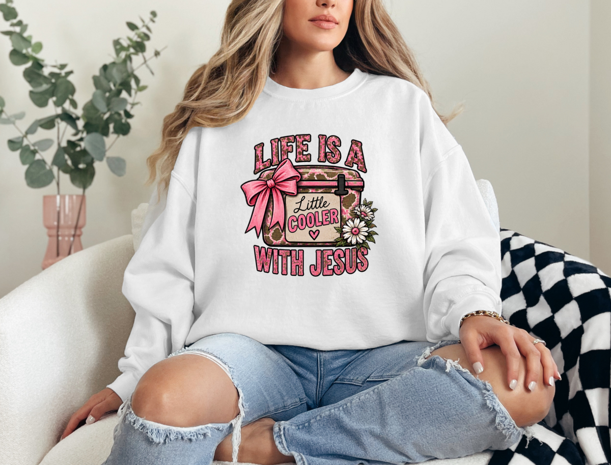 Woman wearing white crewneck sweatshirt with pink cow print cooler, bow, and daisies design that says Life Is a Little Cooler With Jesus