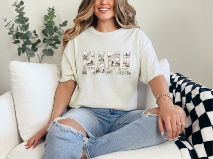 A woman sitting on a white couch wearing a cream-colored graphic t-shirt with the word 'Hawaii' spelled out in decorative letters, paired with distressed light blue jeans.