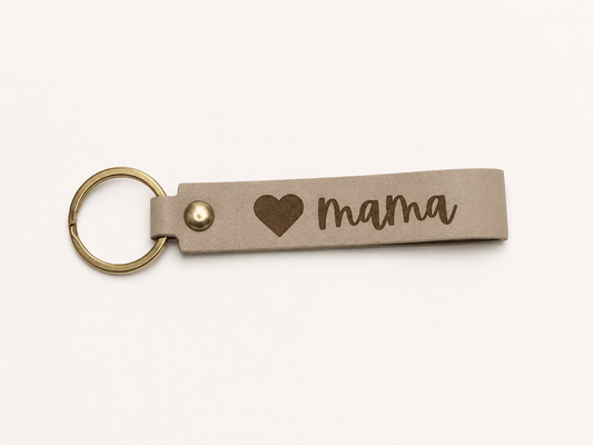 Neutral beige leatherette keychain laser engraved with a heart and the word "Mama" featuring brass-tone hardware.