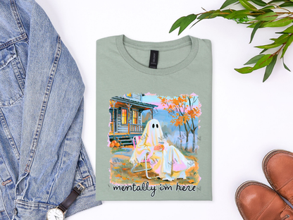 Sage green Mentally I’m Here ghost graphic tee with pumpkins, autumn trees, and colorful cabin artwork