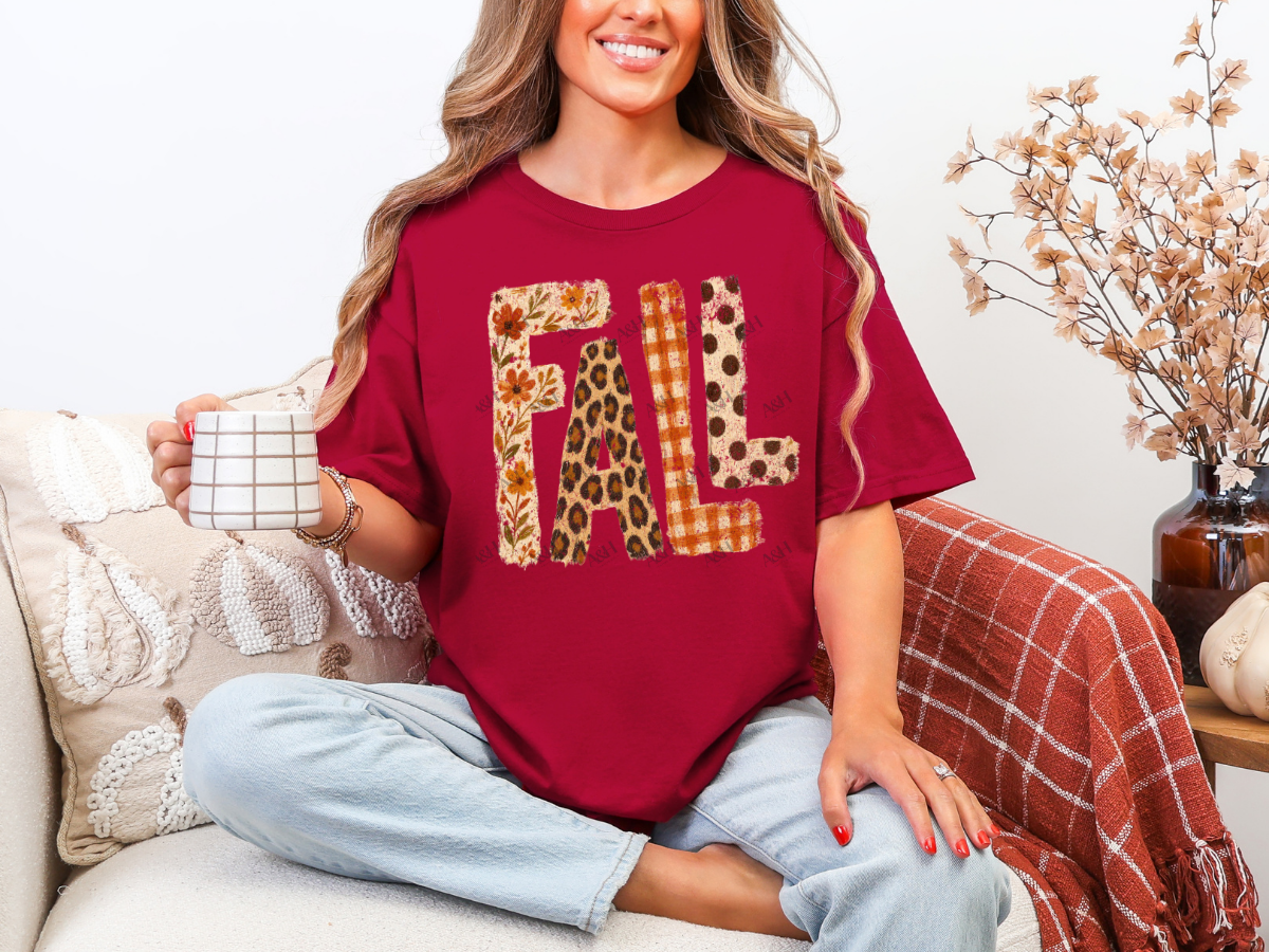 Woman wearing a red FALL graphic tee featuring floral, leopard print, orange plaid, and polka-dot patterns