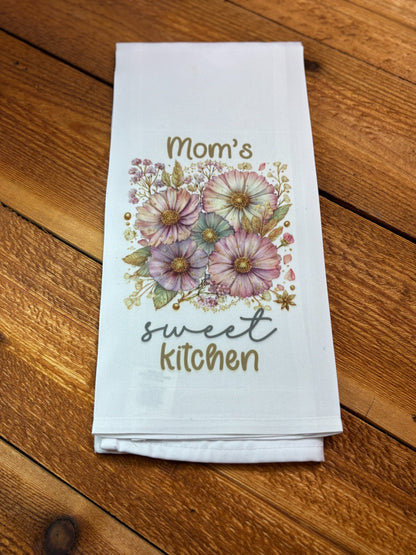 White kitchen tea towel with vintage pink and lavender flowers reading “Mom’s Sweet Kitchen,” part of a floral tea towel set