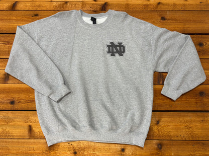Front of a gray crewneck sweatshirt with a small black interlocking ND monogram on the left chest.