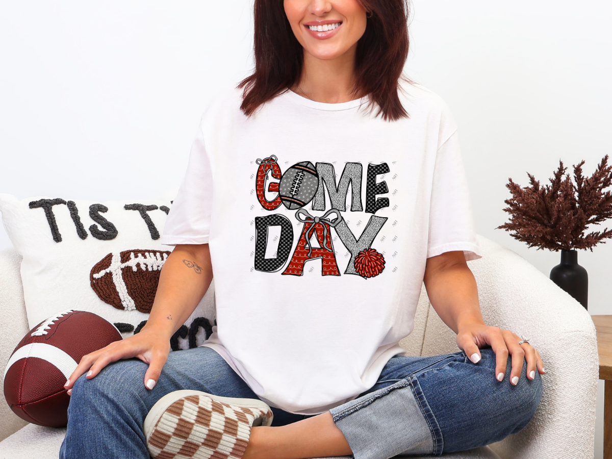 Model wearing a white red and black Game Day football graphic tee with bows and checkerboard details.