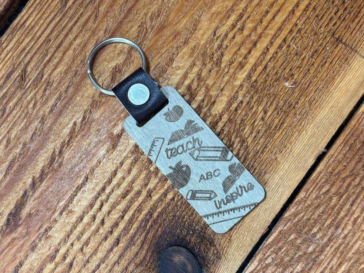 Teacher keychain with teach, ABC, inspire, apples, books, pencils, and rulers on a rectangular tag.