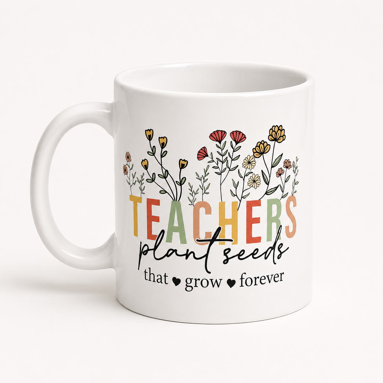 White ceramic coffee mug featuring colorful flowers and the inspirational quote "Teachers Plant Seeds That Grow Forever."