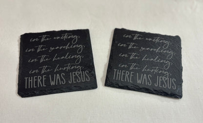 Two square black slate coasters engraved with script lettering about waiting, searching, healing and hurting, ending “There Was Jesus.”