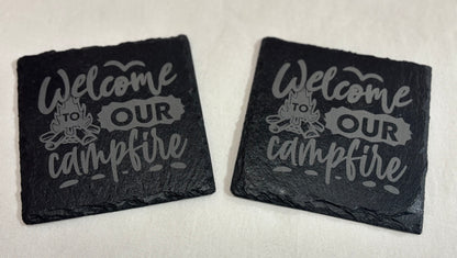 Two square black slate coasters engraved with “Welcome to Our Campfire” lettering and a campfire illustration.